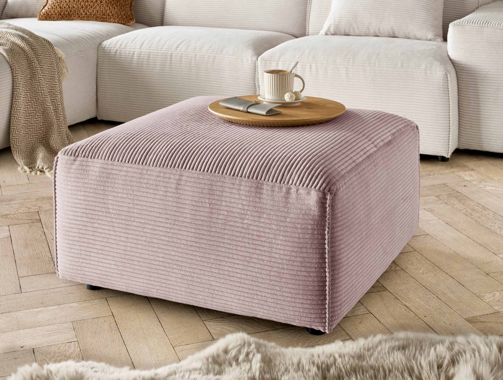 Lounge Handmade Hocker LH-EDINA Hocker in rosa Cordstoff, quadratisch, mit einer Tasse und einem Teller darauf, in einem Wohnzimmer mit Holzboden, seitliche Perspektive