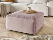 Hocker in rosa Cordstoff, quadratisch, mit einer Tasse und einem Teller darauf, in einem Wohnzimmer mit Holzboden, seitliche Perspektive