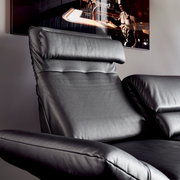 Nahaufnahme eines schwarzen Ledersofas mit verstellbarer Kopfstütze und Armlehne, seitliche Perspektive