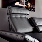Nahaufnahme eines schwarzen Ledersofas mit verstellbarer Kopfstütze und Armlehne, seitliche Perspektive
