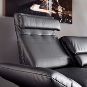 Nahaufnahme eines schwarzen Ledersofas mit verstellbarer Kopfstütze und Armlehne, seitliche Perspektive