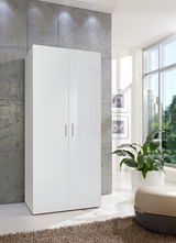 Moderner weißer Kleiderschrank mit zwei Türen, frontal fotografiert, in einem hellen Raum mit großen Fenstern und einer Pflanze im Vordergrund.