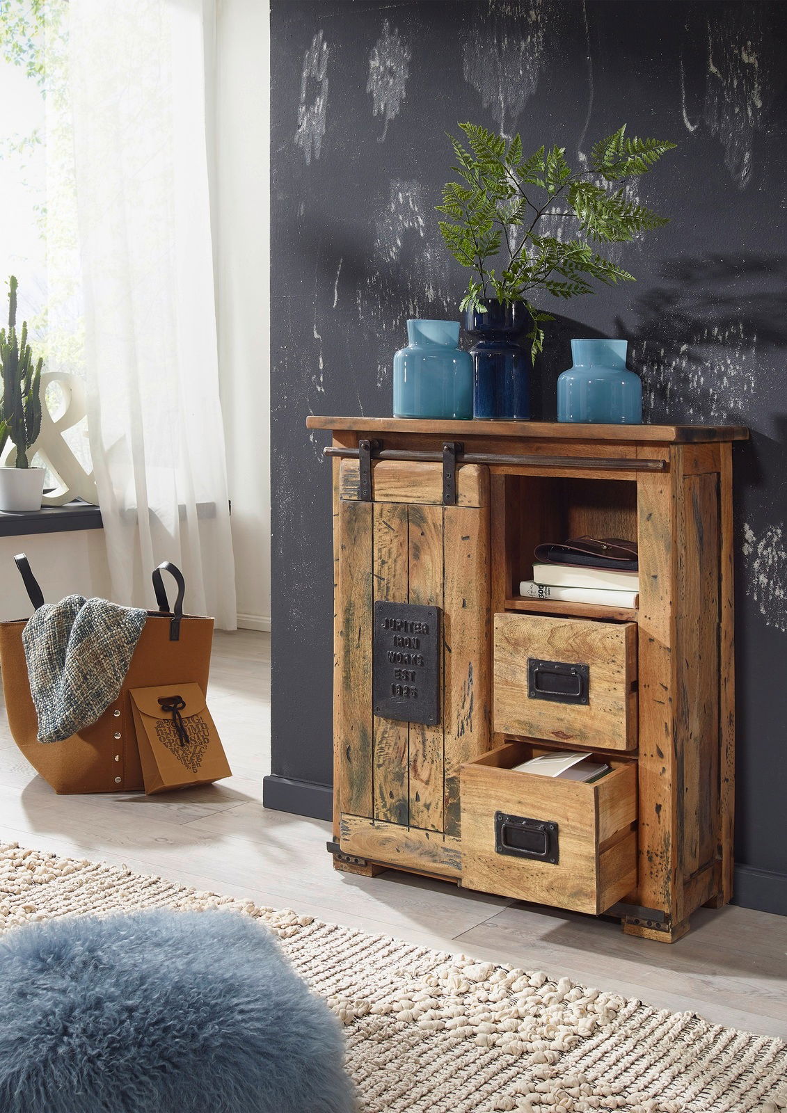 Rustikales Sideboard aus Holz mit Schiebetür und Schubladen, dekoriert mit blauen Vasen, aus der Perspektive von vorne rechts.