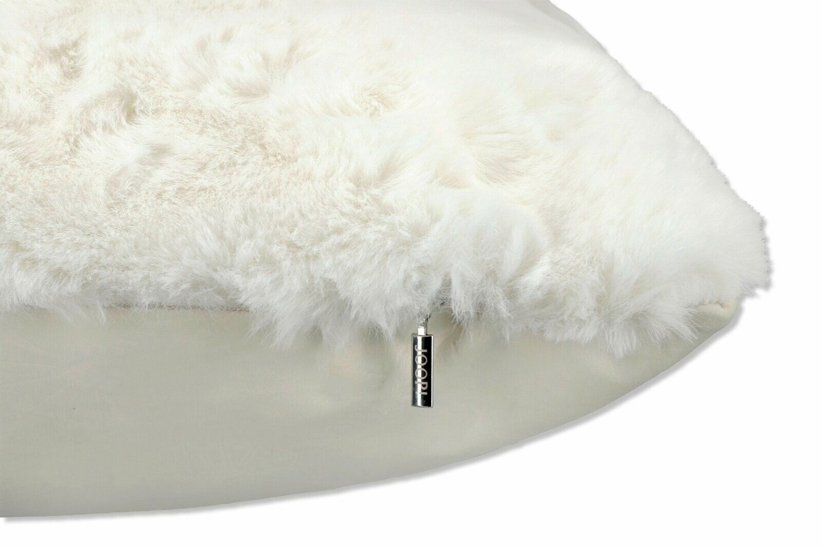 Nahaufnahme eines flauschigen weißen Kissens mit einem kleinen JOOP!-Anhänger an der Seite.