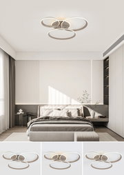 Moderne led-plafondlamp met drie in elkaar verweven ringen, van onderaf gezien in een stijlvolle slaapkamer.