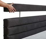 Nahaufnahme eines dunkelgrauen Boxspringbett-Kopfteil mit einer Hand, die das obere Polster hält, seitliche Perspektive.