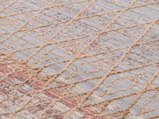 Nahaufnahme eines Designer-Teppichs mit geometrischem Muster in Beige- und Grautönen, diagonale Perspektive