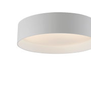 Witte, ronde plafondlamp met een platte, moderne kap en een warm lichtgevende diffuser tegen een grijze achtergrond, gezien van onderaf in een licht onderaanzicht (close-up).