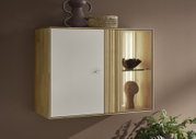Wandhangende houten opbergkast met witte deur, verticale lamellen en verlichte glazen vitrine met decoratie, gefotografeerd in schuin vooraanzicht