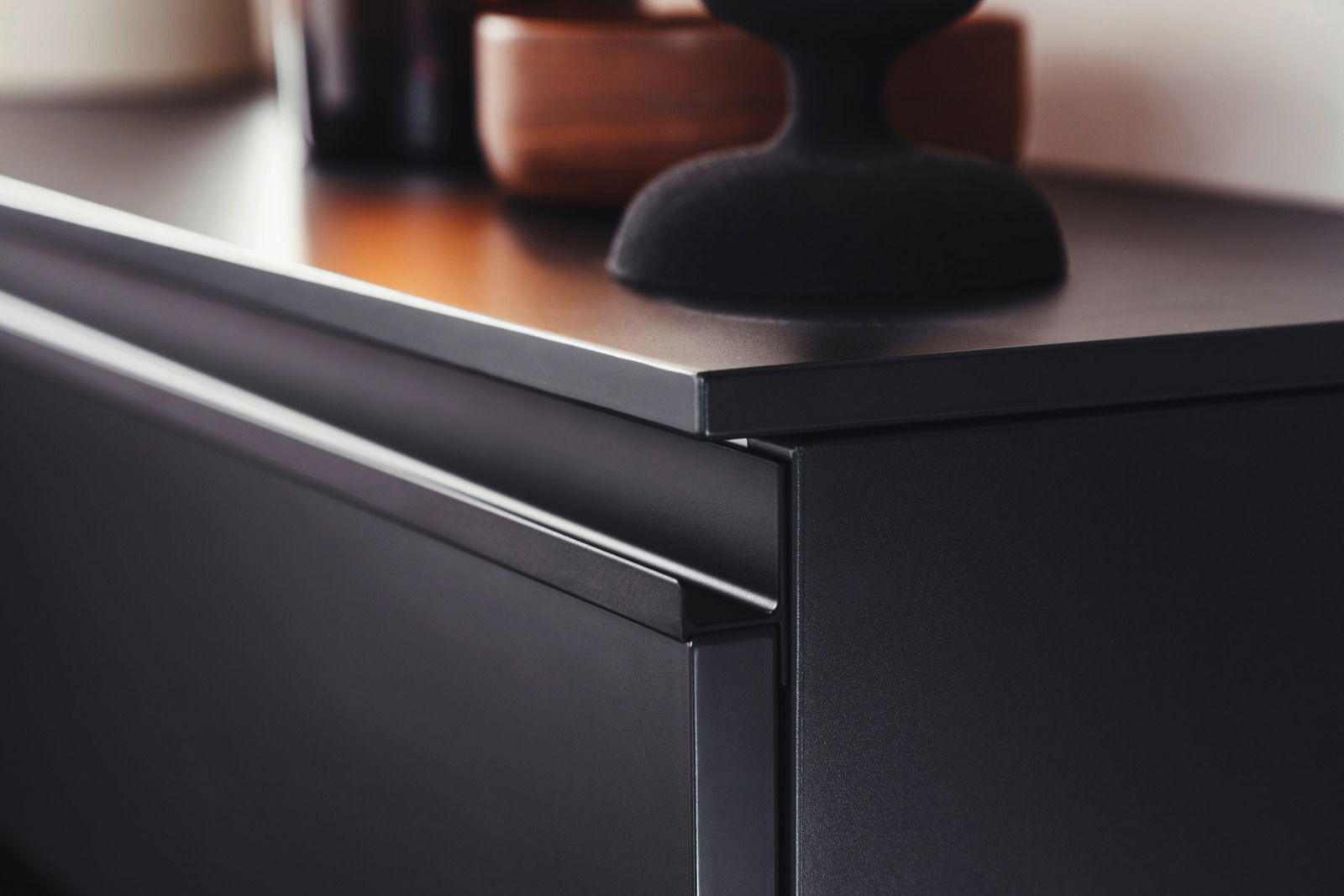 Nahaufnahme eines modernen, schwarzen Hänge-Schuhschranks mit glatter Oberfläche und eleganter Kante, seitliche Perspektive.