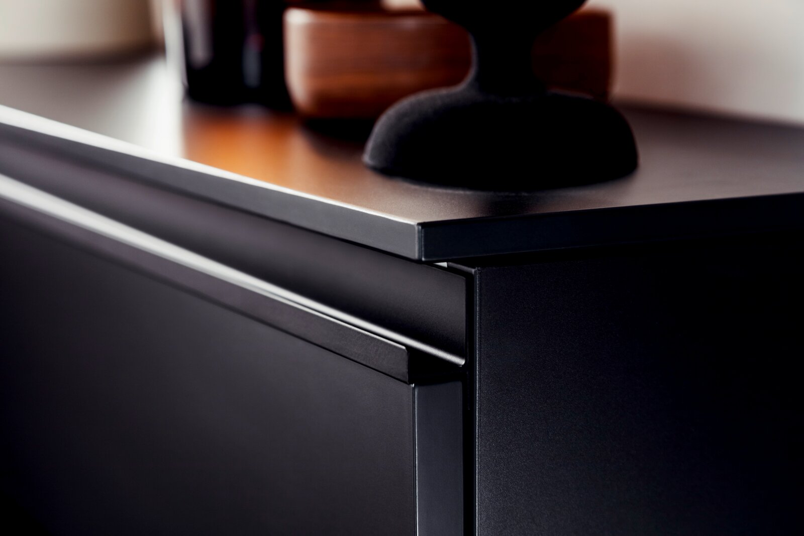 Nahaufnahme eines modernen, schwarzen Hänge-Schuhschranks mit glatter Oberfläche und eleganter Kante, seitliche Perspektive.