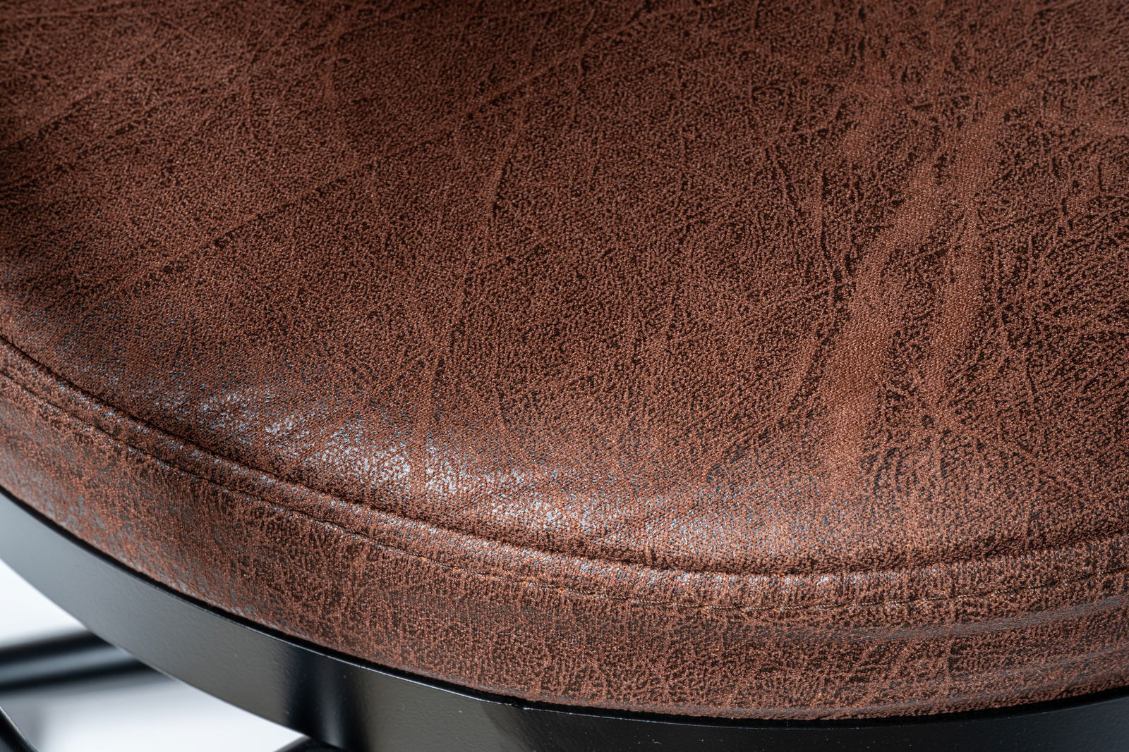 Nahaufnahme eines braunen Drehstuhlsitzes mit strukturierter Oberfläche und schwarzem Metallgestell, von oben betrachtet.
