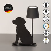 Akku-Tischleuchte mit schwarzer Silhouette eines sitzenden Hundes, seitliche Perspektive. Made in Germany, USB-Anschluss, Touch-Bedienung, CCT-Funktion, 4 Stunden Ladezeit, bis zu 50 Stunden Leuchtdauer.