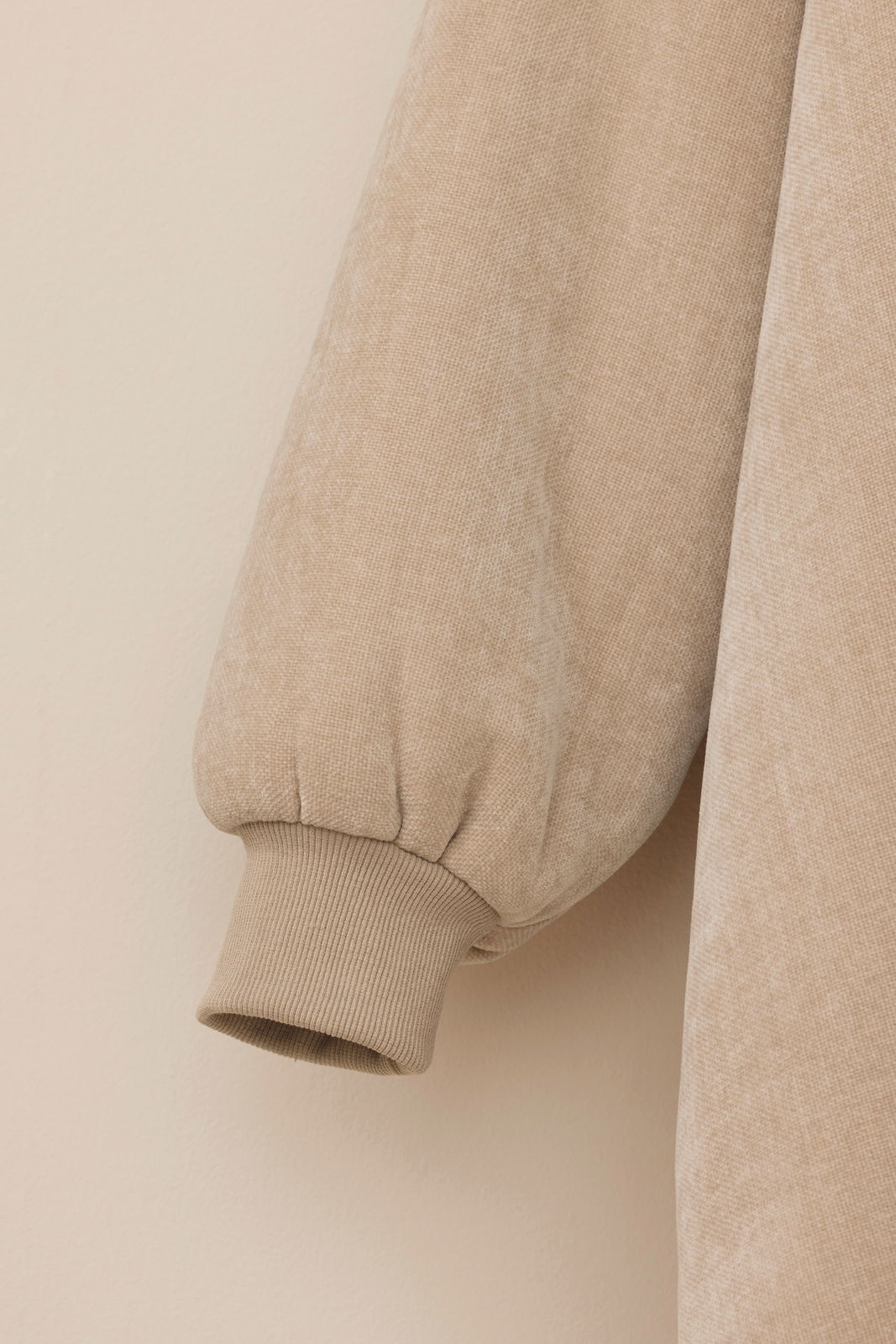 Nahaufnahme eines beigen Lounge Hoodies mit geripptem Bündchen, seitliche Perspektive