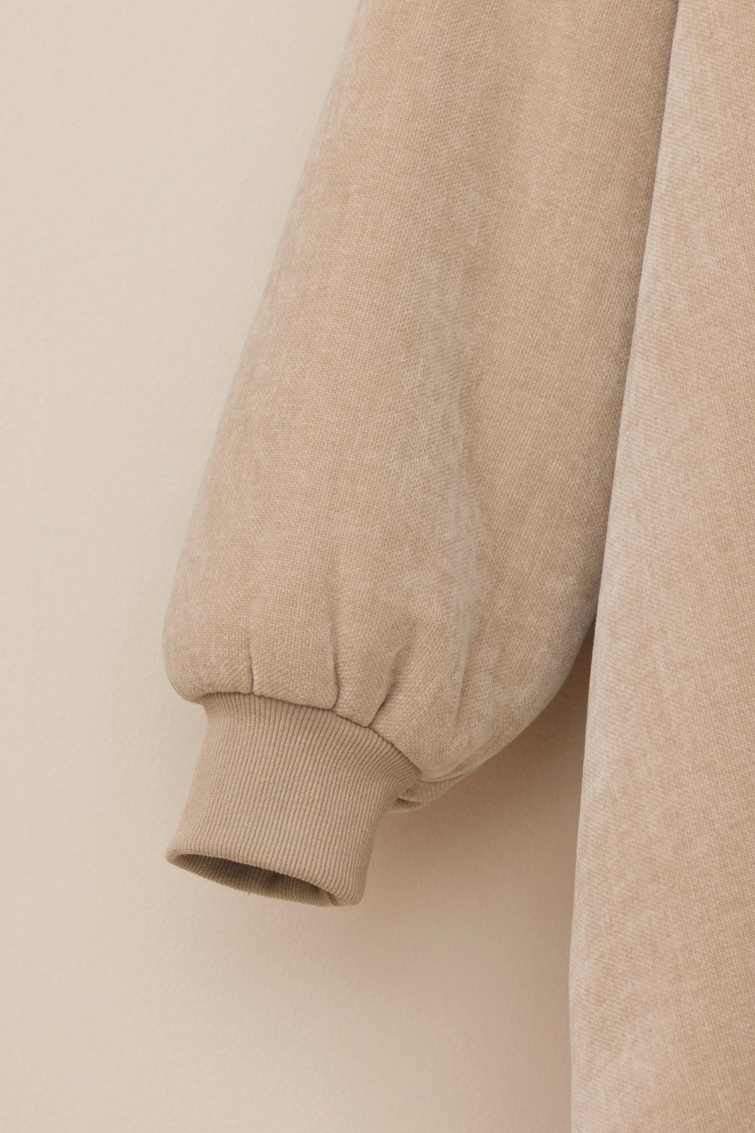 Nahaufnahme eines beigen Lounge Hoodies mit geripptem Bündchen, seitliche Perspektive