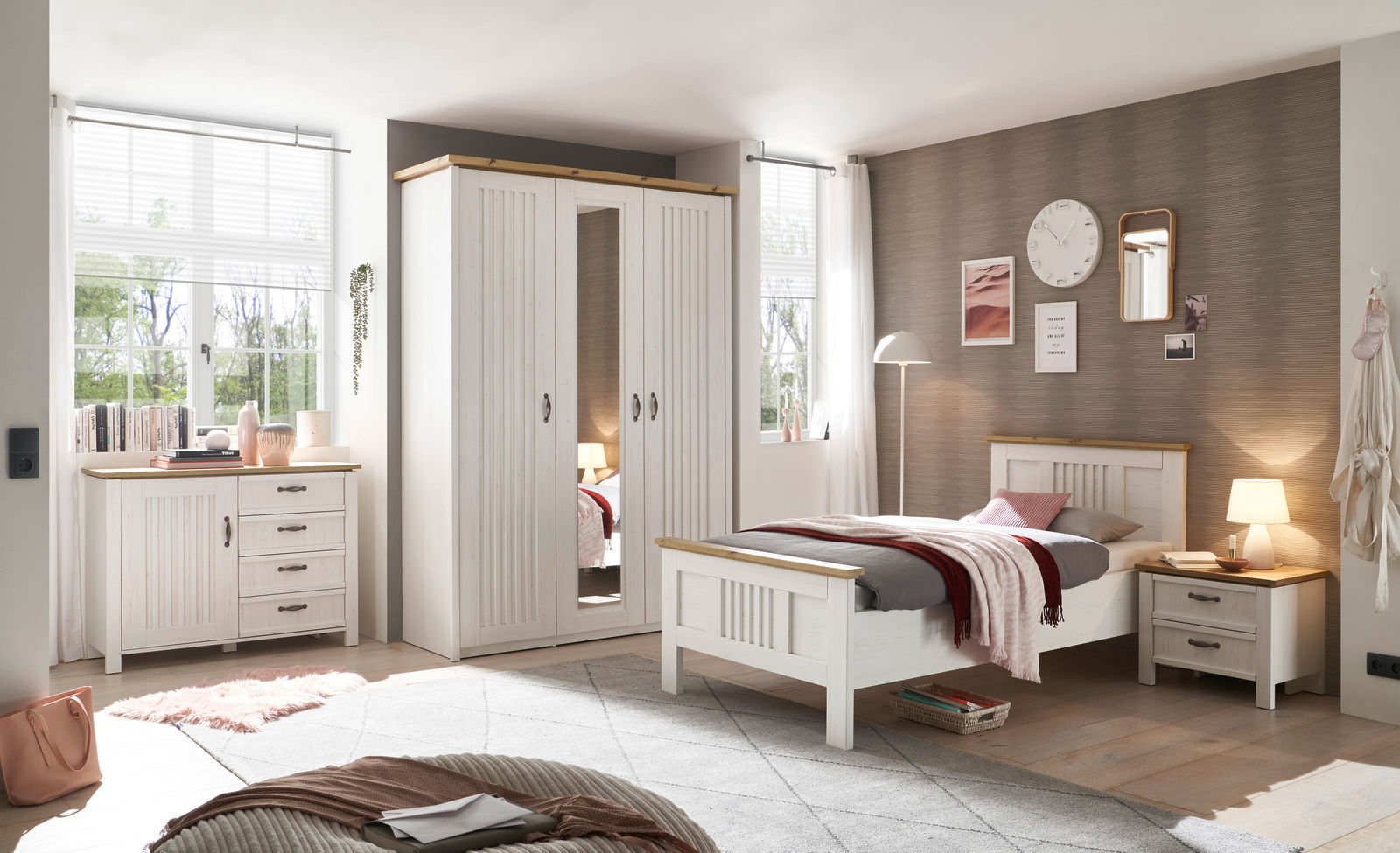 Schlafzimmer mit weißem Kleiderschrank, Bett und Kommode aus Holz, seitliche Perspektive