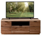Frontansicht eines großen Flachbildfernsehers auf einem modernen TV-Lowboard aus hellem Holz mit mehreren Schubladen und offenem Mittelfach; auf dem Bildschirm ist eine sonnige Waldlichtung zu sehen.