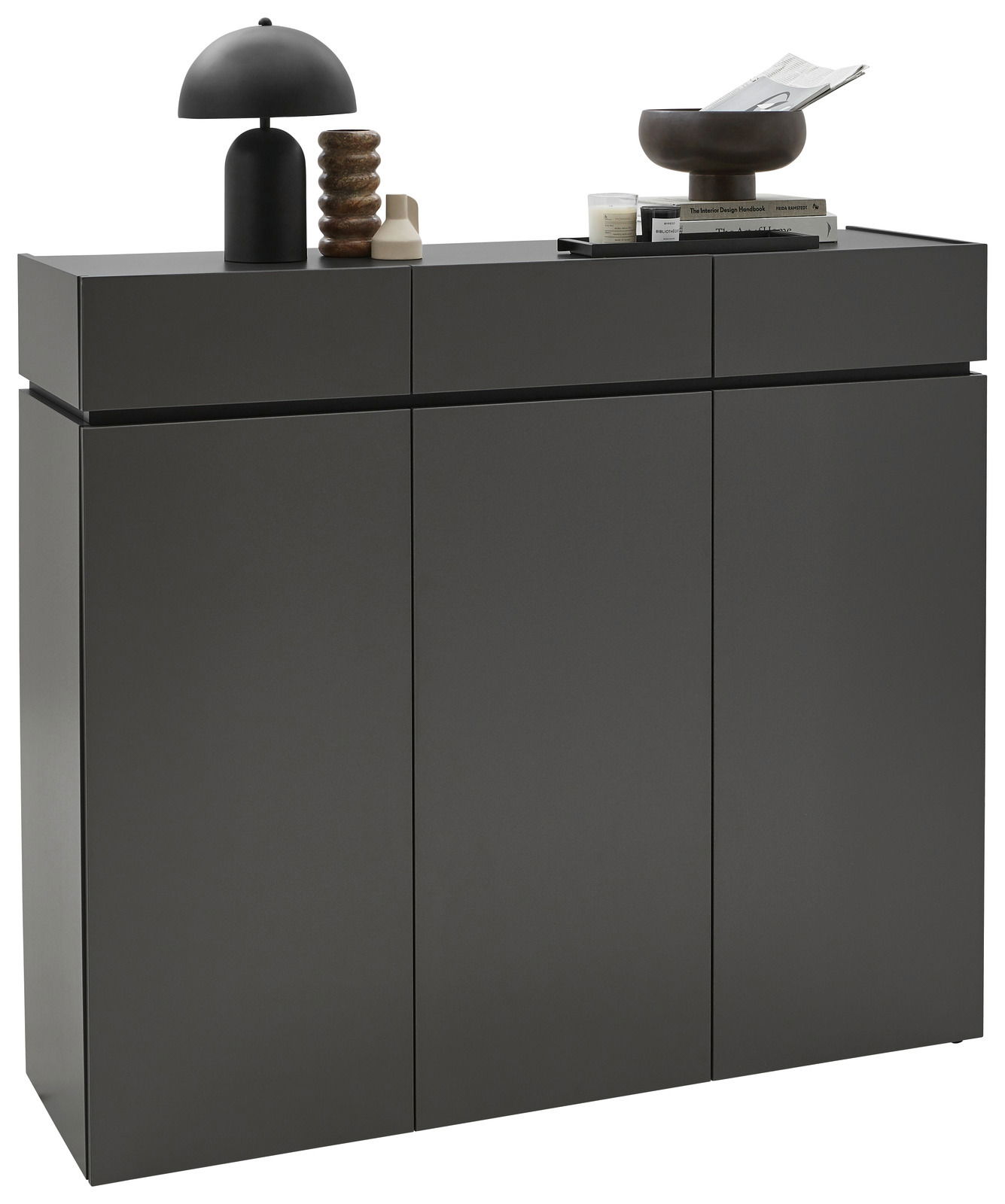 Voleo XL-Schuhschrank UNIQUE Moderner XL-Schuhschrank H121 in dunklem Grau mit drei Türen, dekoriert mit einer schwarzen Lampe, einer Skulptur und Büchern, seitliche Perspektive.