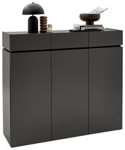 Moderner XL-Schuhschrank H121 in dunklem Grau mit drei Türen, dekoriert mit einer schwarzen Lampe, einer Skulptur und Büchern, seitliche Perspektive.