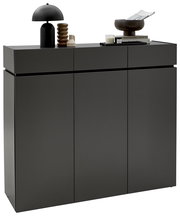 Moderner XL-Schuhschrank H121 in dunklem Grau mit drei Türen, dekoriert mit einer schwarzen Lampe, einer Skulptur und Büchern, seitliche Perspektive.