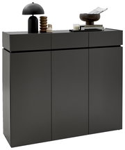 Moderner XL-Schuhschrank H121 in dunklem Grau mit drei Türen, dekoriert mit einer schwarzen Lampe, einer Skulptur und Büchern, seitliche Perspektive.