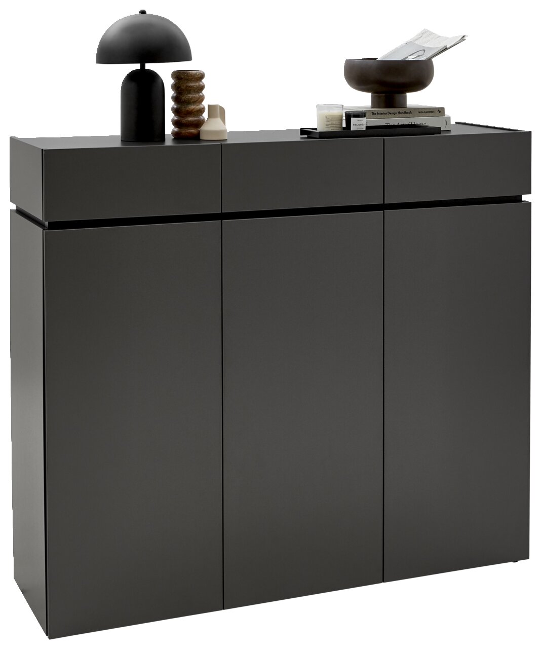 Voleo XL-schoenenkast UNIQUE Moderner XL-Schuhschrank H121 in dunklem Grau mit drei Türen, dekoriert mit einer schwarzen Lampe, einer Skulptur und Büchern, seitliche Perspektive.