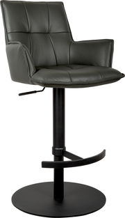 Dunkelgrauer, gepolsterter Barhocker mit Armlehnen, Steppnähten, schwarzer Säule, rundem Tellerfuß und Fußstütze, in leichter Frontansicht von schräg links freigestellt