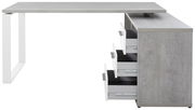 Moderner Eckschreibtisch in Betonoptik mit weißen Metallbeinen und mehreren offenen Schubladen, seitliche Perspektive.