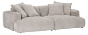 Beiges, modernes Lounge-Sofa mit extra tiefer Sitzfläche, breiten Armlehnen und mehreren Rückenkissen, freigestellt auf weißem Hintergrund, in schräger Frontansicht von links.