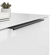 Nahaufnahme einer modernen weißen Nachtkommode mit schwarzem Griff, dekoriert mit einem kleinen Pflanzentopf und Büchern.