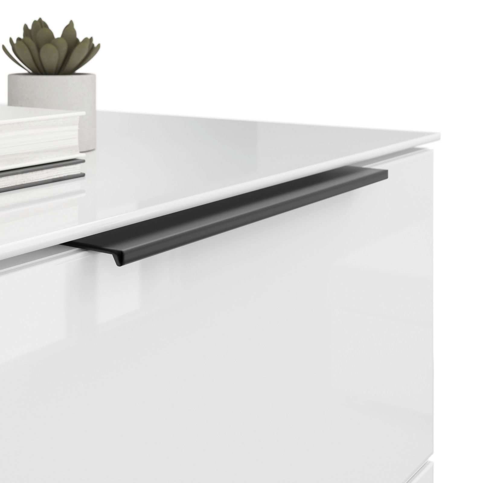 Nahaufnahme einer modernen weißen Nachtkommode mit schwarzem Griff, dekoriert mit einem kleinen Pflanzentopf und Büchern.