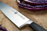 Kochmesser 20cm VIER STERNE auf einem Holzbrett, neben geschnittenem Rotkohl, in Nahaufnahme von der Seite.