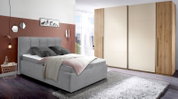Graues Polsterbett in modernem Schlafzimmer, seitliche Perspektive