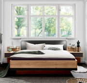 Modernes Futonbett aus Holz mit gepolstertem Kopfteil, umgeben von Nachttischen, in einem hellen Raum mit großen Fenstern, Vorderansicht