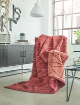 Rote Jacquard-Decke 150x200 cm mit Blattmuster, drapiert über einem Sessel in einem modernen Wohnzimmer mit Blick auf Fenster und Dekoration.