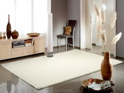 Heller Uni-Teppich in einem modernen Wohnzimmer, fotografiert aus einer seitlichen Perspektive. Der Raum ist mit stilvollen Dekorationen und Möbeln ausgestattet.