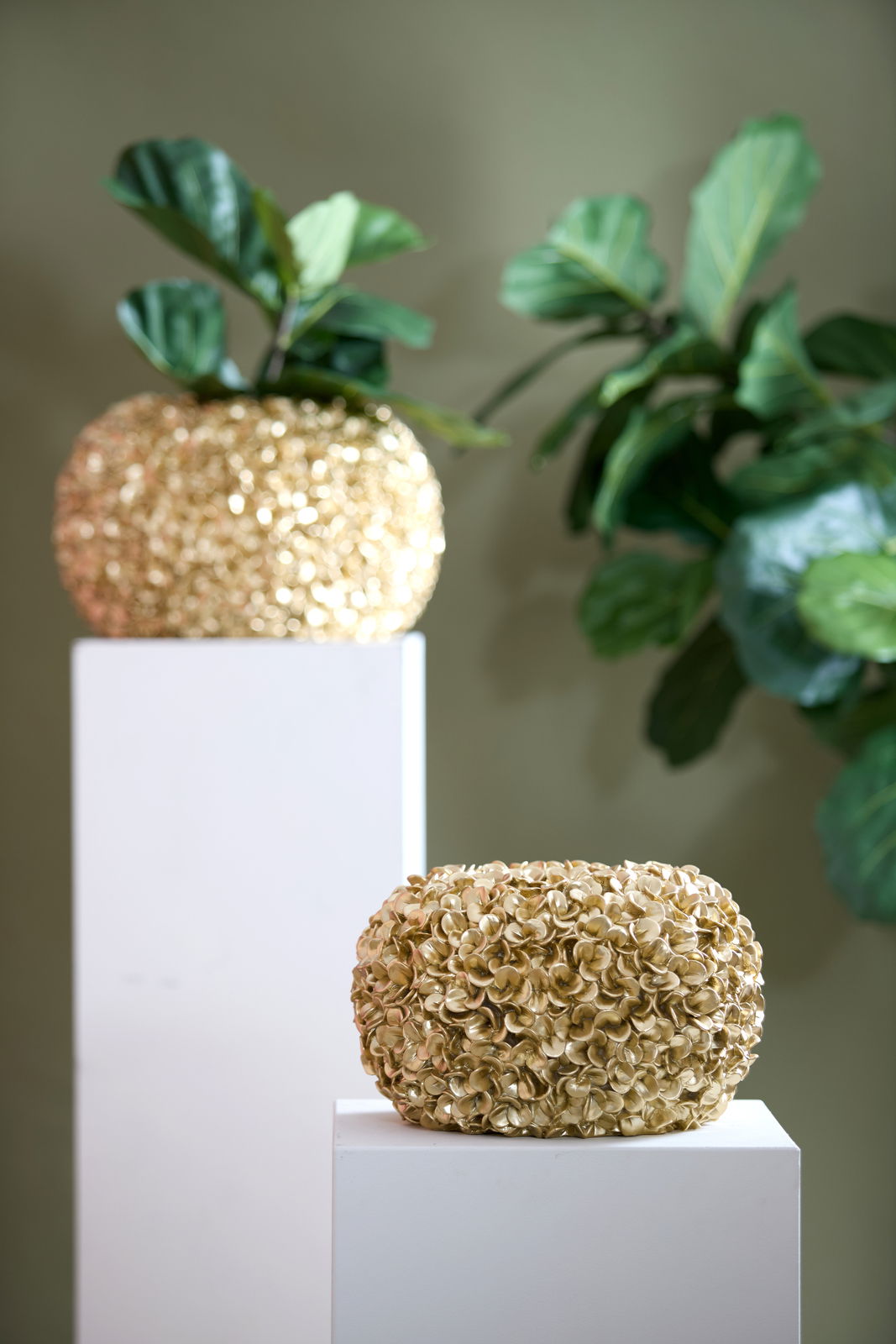 Goldene Vase mit blütenartiger Struktur, auf einem weißen Podest präsentiert, seitliche Perspektive