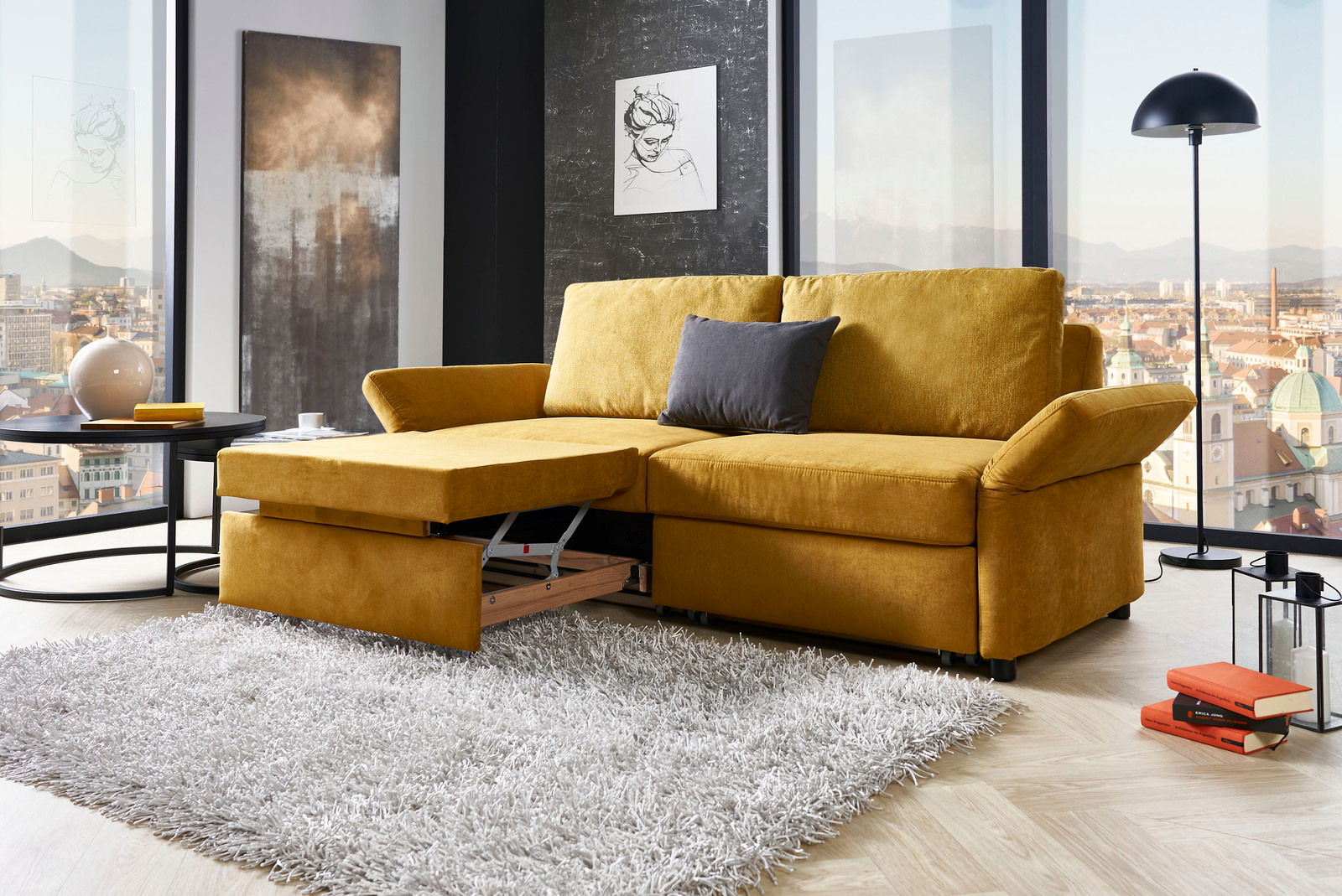 Gelbes Funktionssofa in modernem Wohnzimmer mit Stadtblick, von vorne betrachtet.