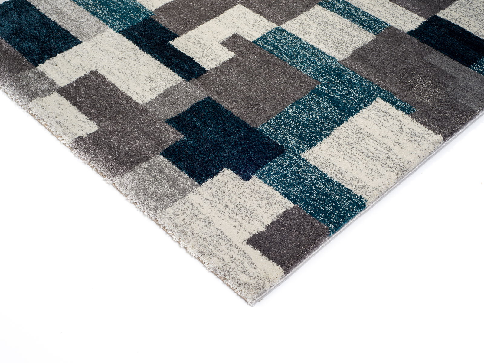 Frisé-Teppich mit geometrischem Muster in Blau-, Grau- und Weißtönen, perspektivisch von der Ecke aufgenommen.