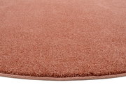 Nahaufnahme eines runden, einfarbigen Teppichs in Rosa mit weicher Textur.