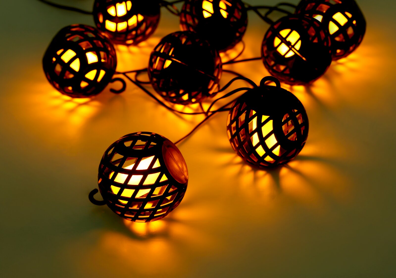 Nahaufnahme einer Solar-Lichterkette mit leuchtenden, kugelförmigen Lampen in einem dekorativen Gitterdesign, die warmes Licht abstrahlen.
