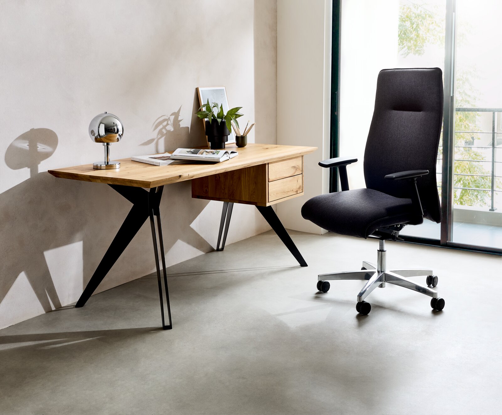 Moderner Schreibtisch aus Holz mit schwarzen Metallbeinen, dekoriert mit einer Lampe, Pflanzen und Büchern, seitliche Perspektive.