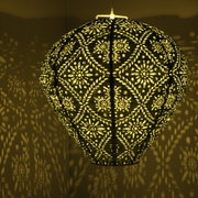 Hangende zonne-lantaarn met filigraanpatroon, die een warm licht en decoratieve schaduwen op de muur werpt, gezien vanaf de zijkant.