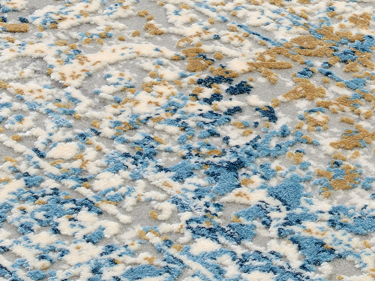 Nahaufnahme eines Designer-Teppichs mit abstraktem Muster in Blau-, Beige- und Grautönen, von oben betrachtet.