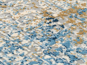 Nahaufnahme eines Designer-Teppichs mit abstraktem Muster in Blau-, Beige- und Grautönen, von oben betrachtet.