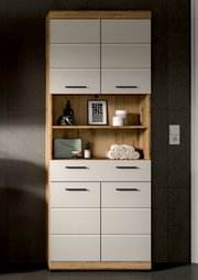Hoher Badezimmer-Hochschrank in Holzoptik mit weißen Fronten und schwarzen Griffen, mittigem offenem Regal mit Deko und Handtüchern, frontale Ansicht