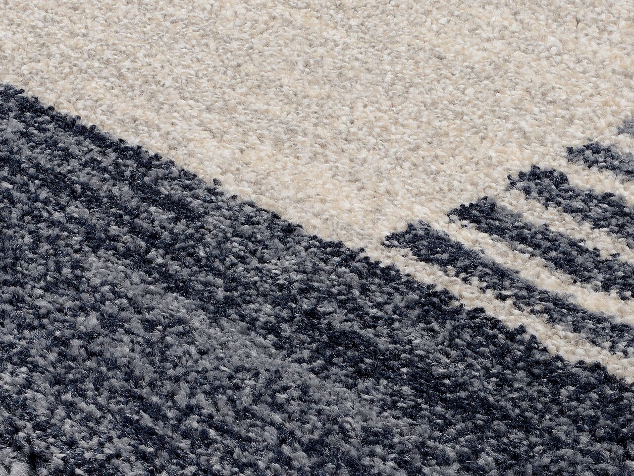 Nahaufnahme eines Frisé-Teppichs mit grauen und cremefarbenen Mustern, diagonale Perspektive.