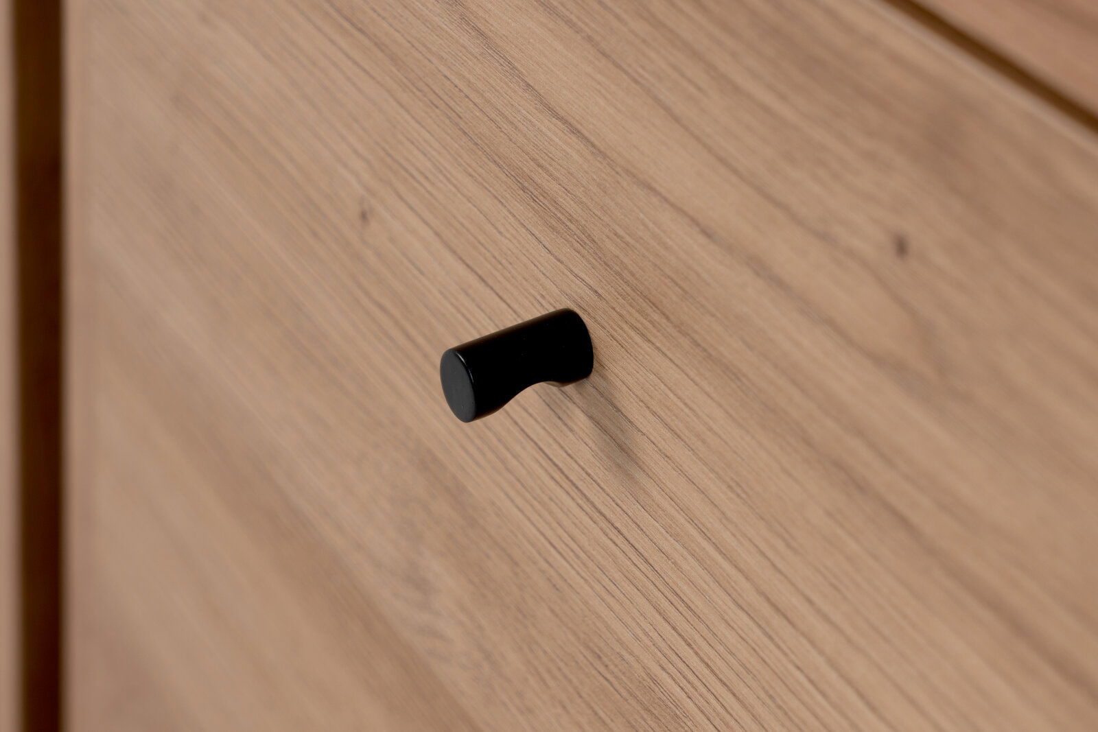 Nahaufnahme eines Holzschranks mit schwarzem Griff, seitliche Perspektive