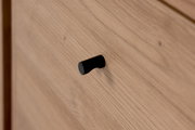 Nahaufnahme eines Holzschranks mit schwarzem Griff, seitliche Perspektive