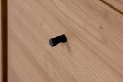 Nahaufnahme eines Holzschranks mit schwarzem Griff, seitliche Perspektive